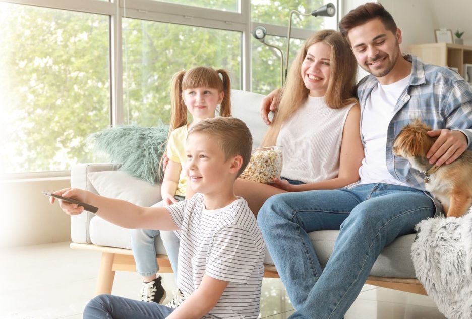A family is sitting on a couch watching tv.