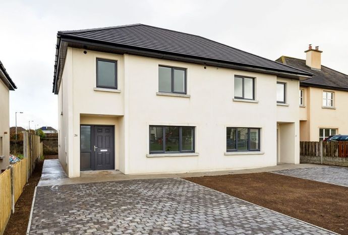 A white house with a black roof and a driveway in front of it.