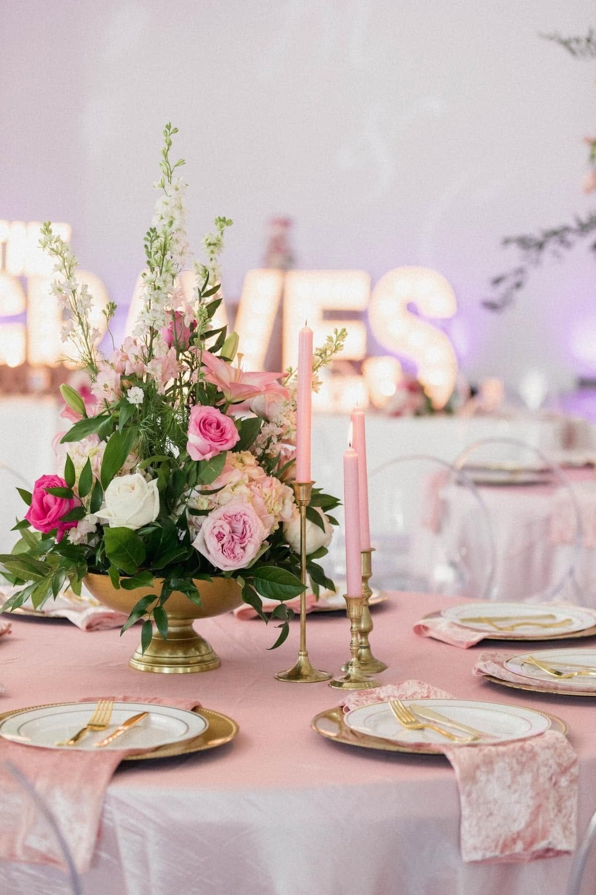 Elegant pink floral table centerpiece with candles and gold accents at a decorated event table