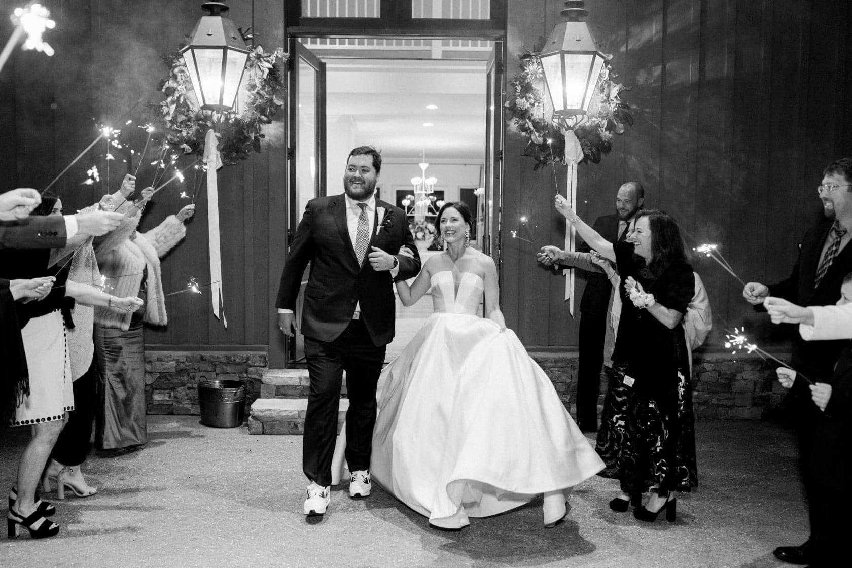 Newlyweds exiting a building through a sparkler sendoff, guests cheering on both sides