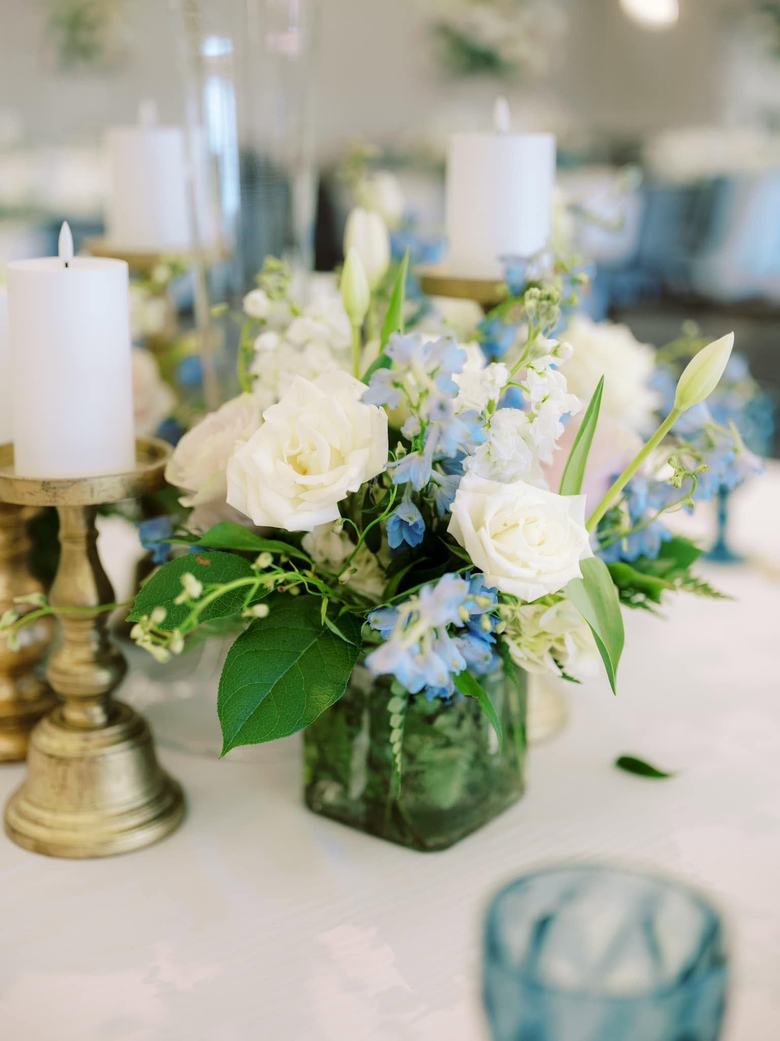 White and blue floral centerpiece with candles on a decorated table