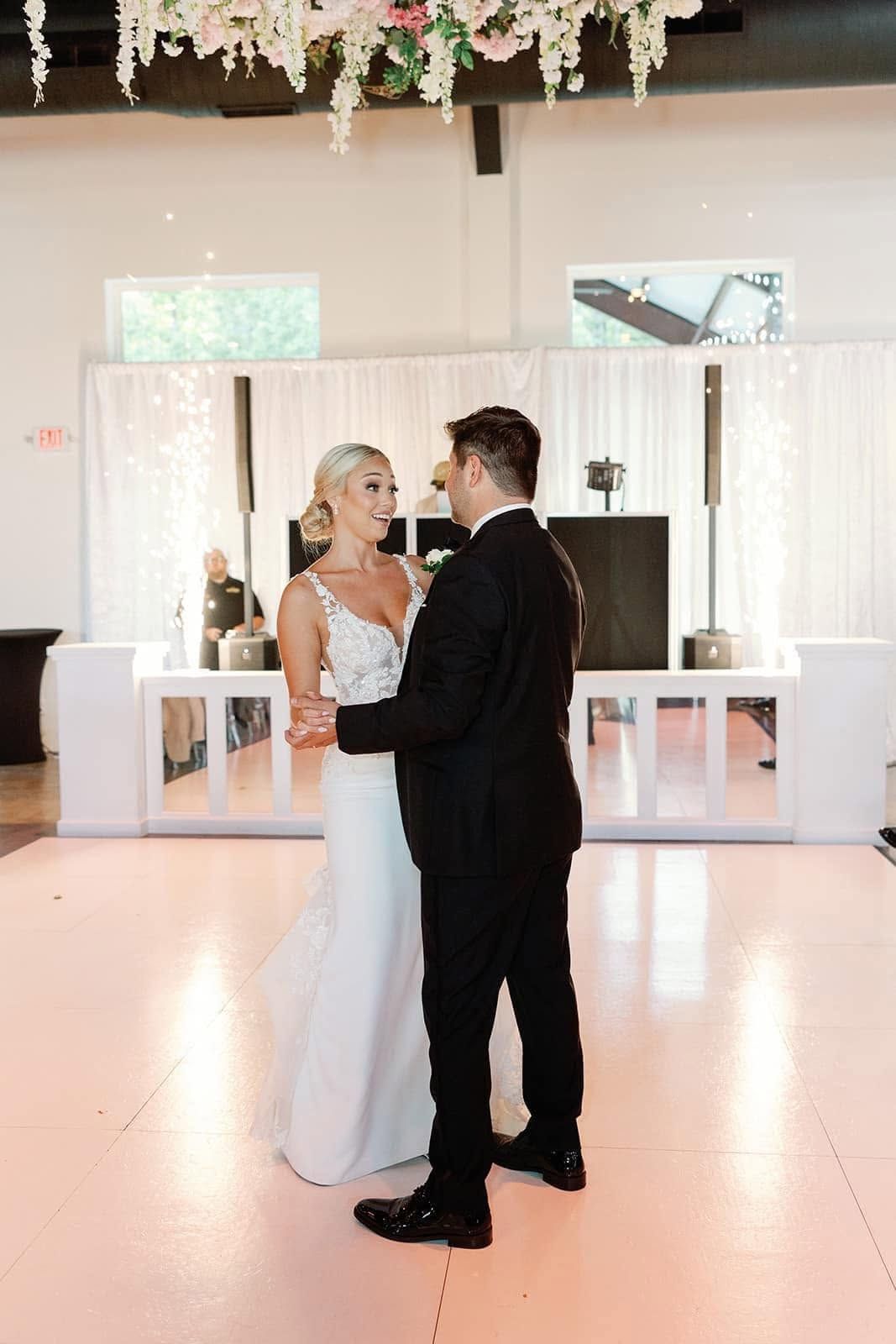 Bride and groom dancing at a wedding reception in a bright, decorated hall