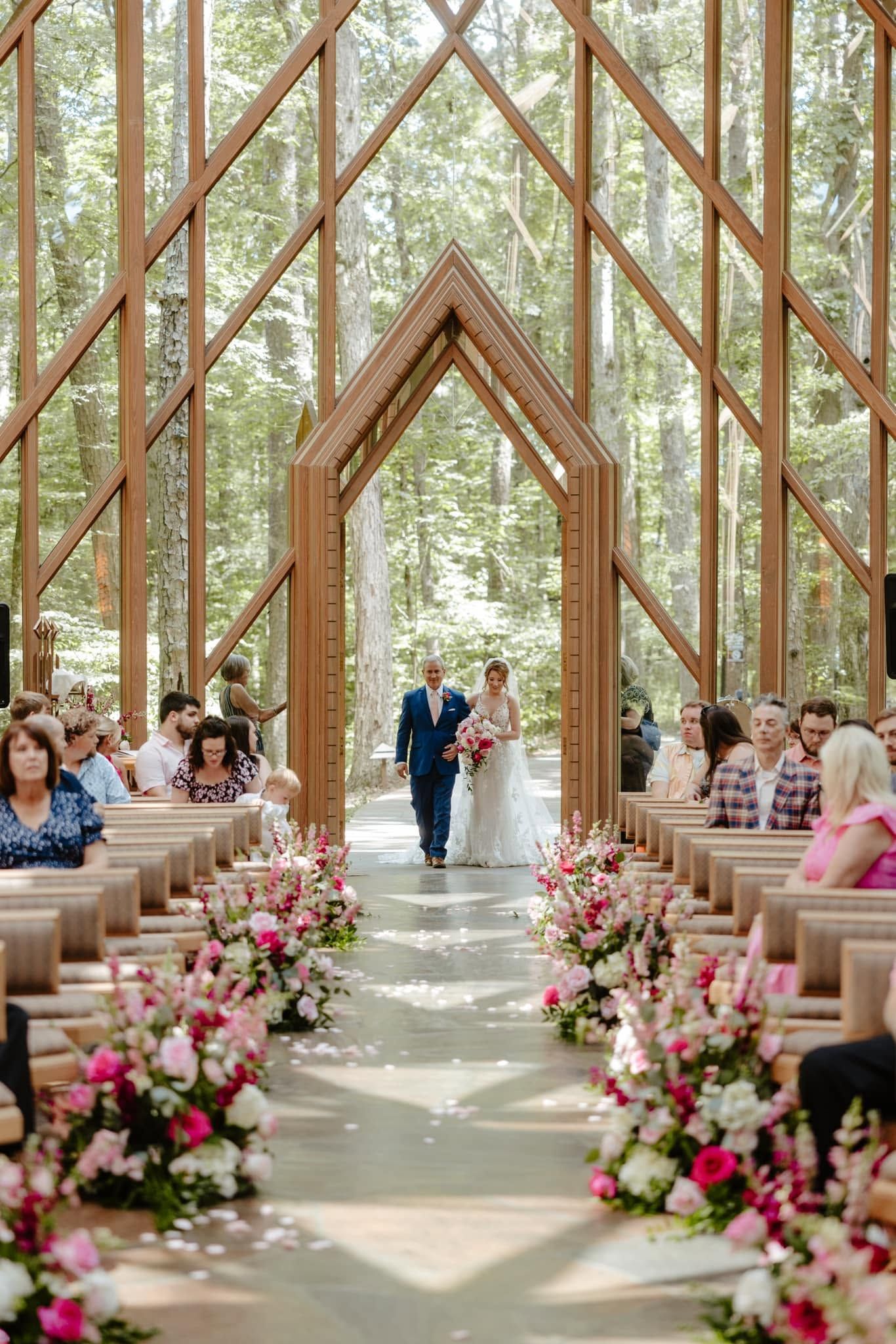 Wedding couple walking down a flower-lined aisle in a wooden garden pavilion