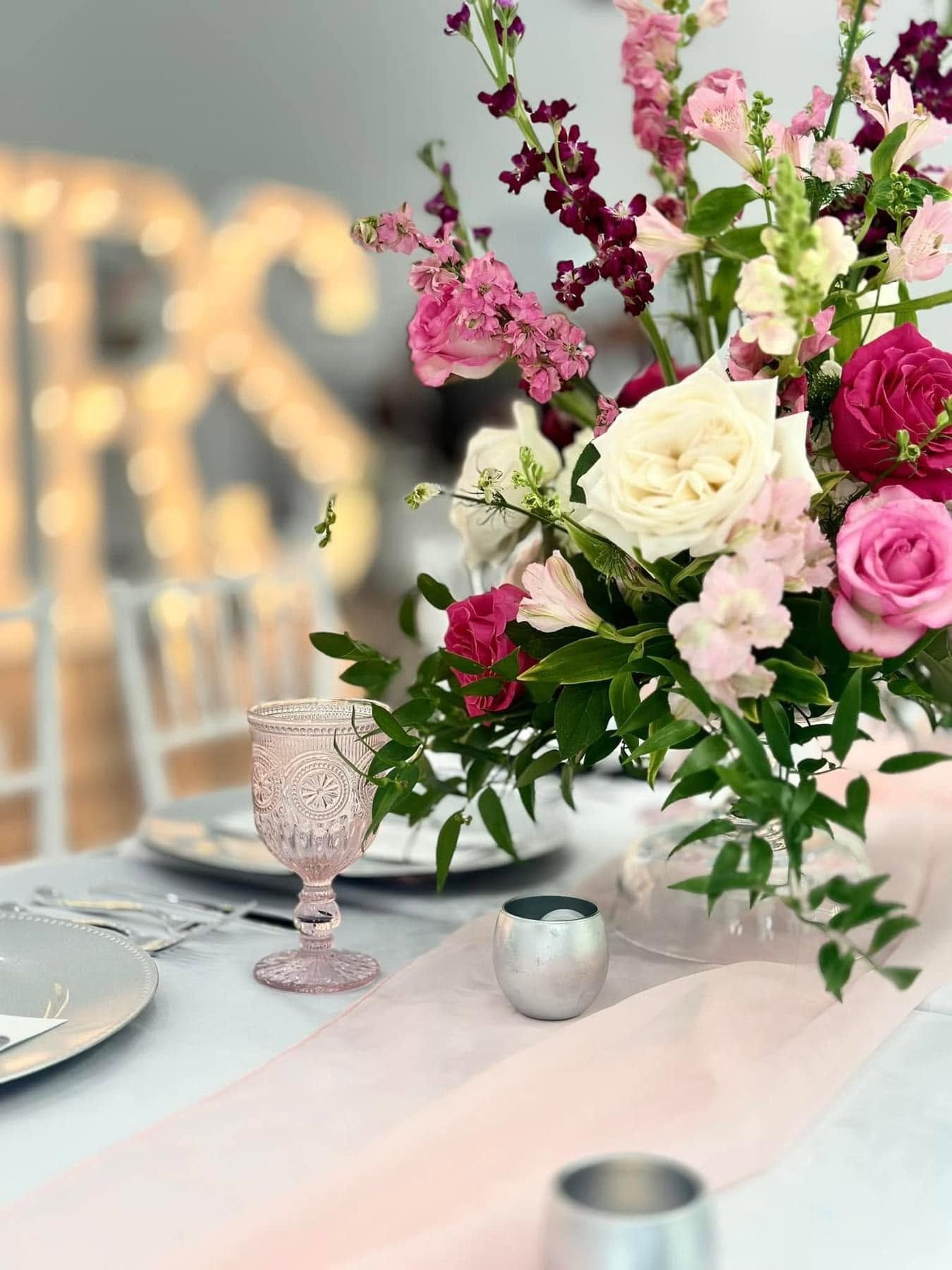 Elegant table setting with pink and white floral centerpiece and soft candlelight