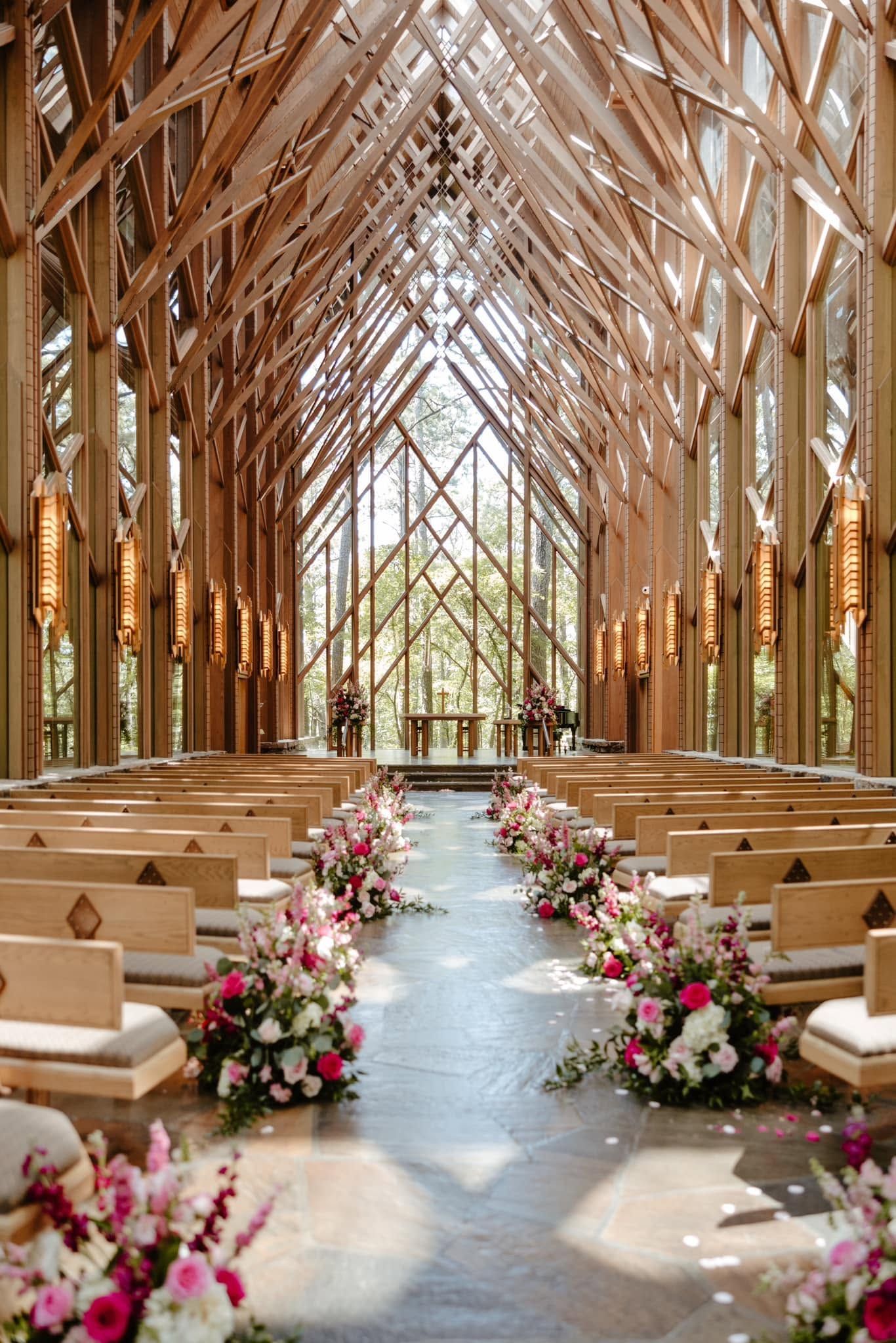 Wooden wedding chapel aisle with floral arrangements and rows of benches under a high vaulted ceiling