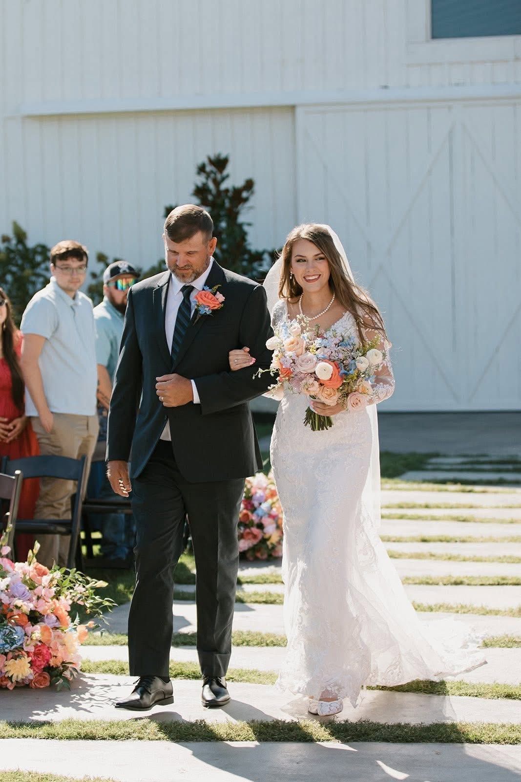 Bride and groom walking down the aisle outdoors, bride holding a bouquet