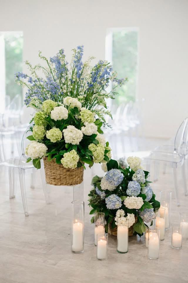 Elegant white and blue floral centerpieces with candles in a bright wedding reception setting