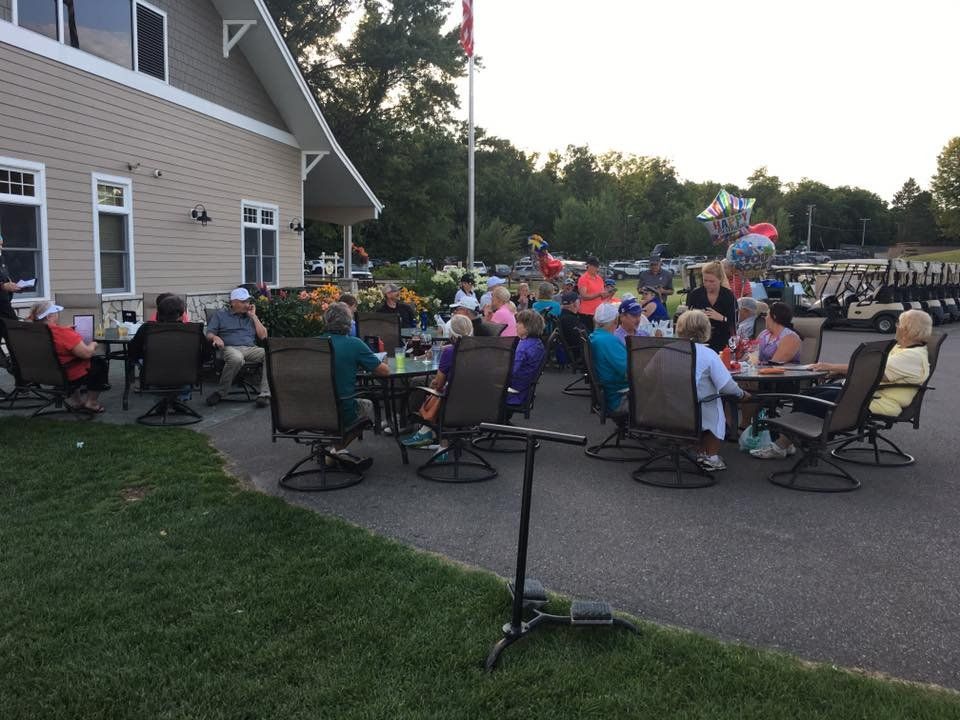 A group of people are sitting at tables outside of a building