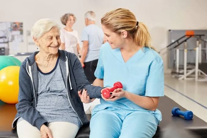 Older woman and nurse exercising with dumbbells in a rehabilitation gym