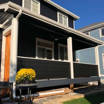 A black house with a porch and yellow flowers on it
