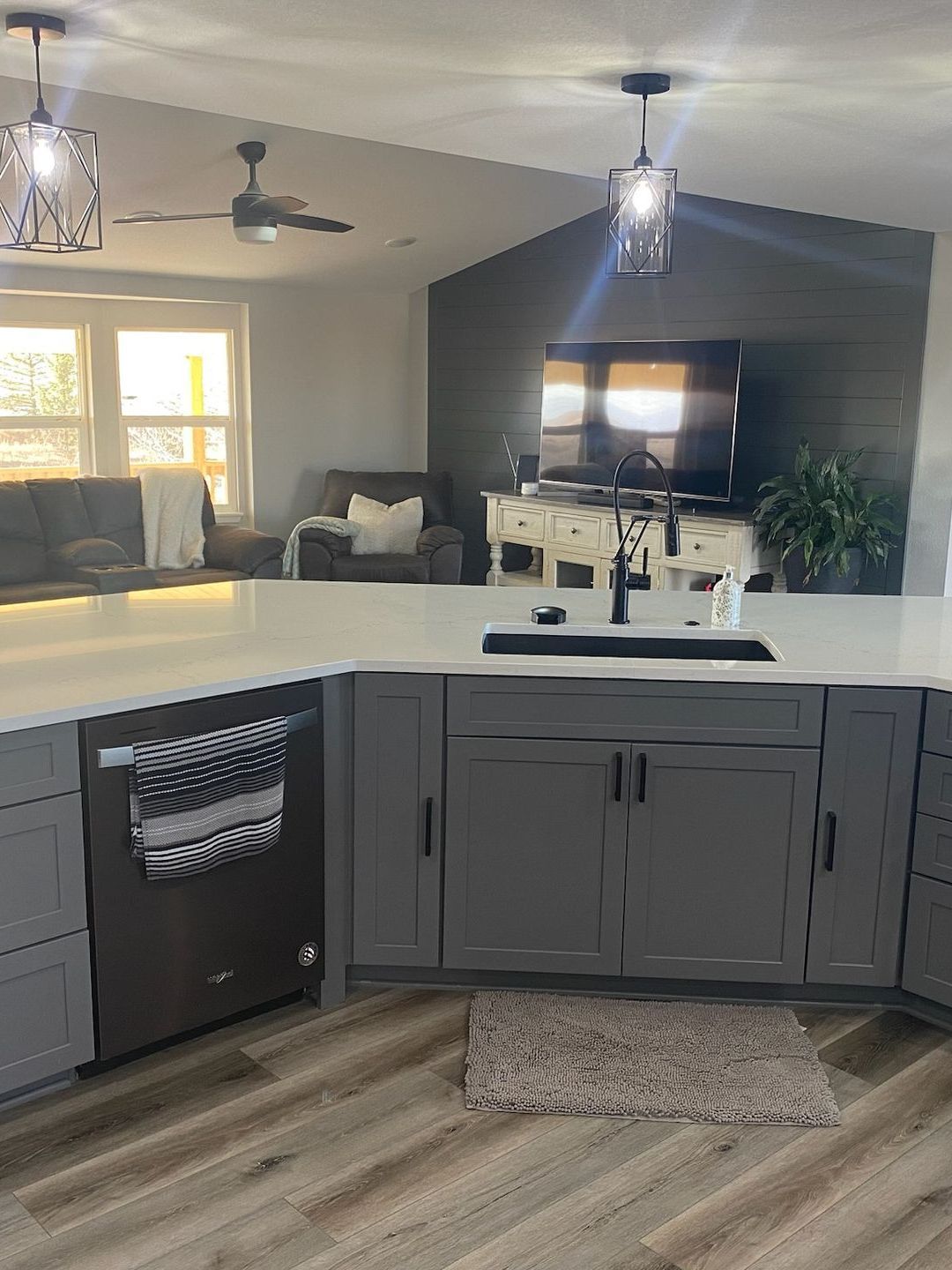 A kitchen with gray cabinets , a sink , a dishwasher , and a television.