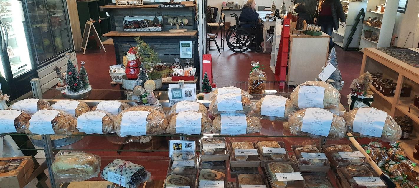 Display case filled with baked goods, wrapped loaves, and small Christmas decorations in a shop.
