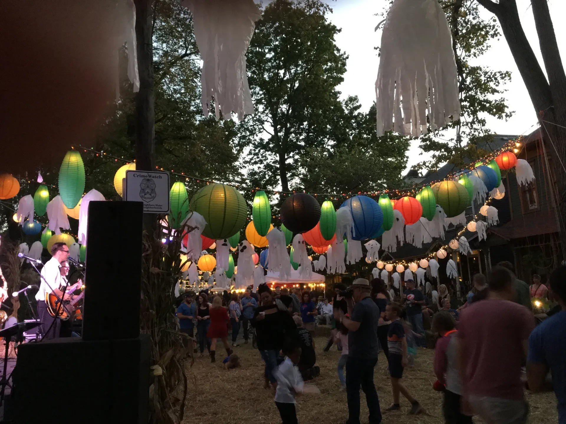 Festival scene with a band performing under colorful lanterns and crowds.