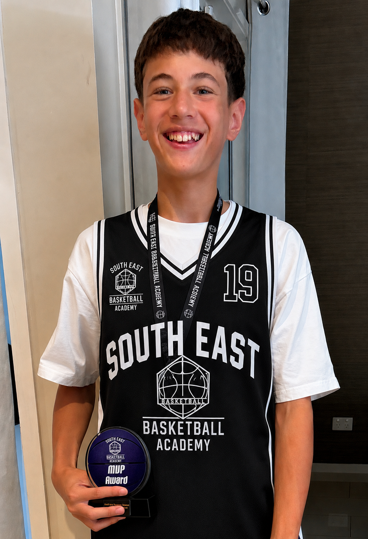 Basketball player holding a ball in front of an Australian flag, wearing a black South East jersey.