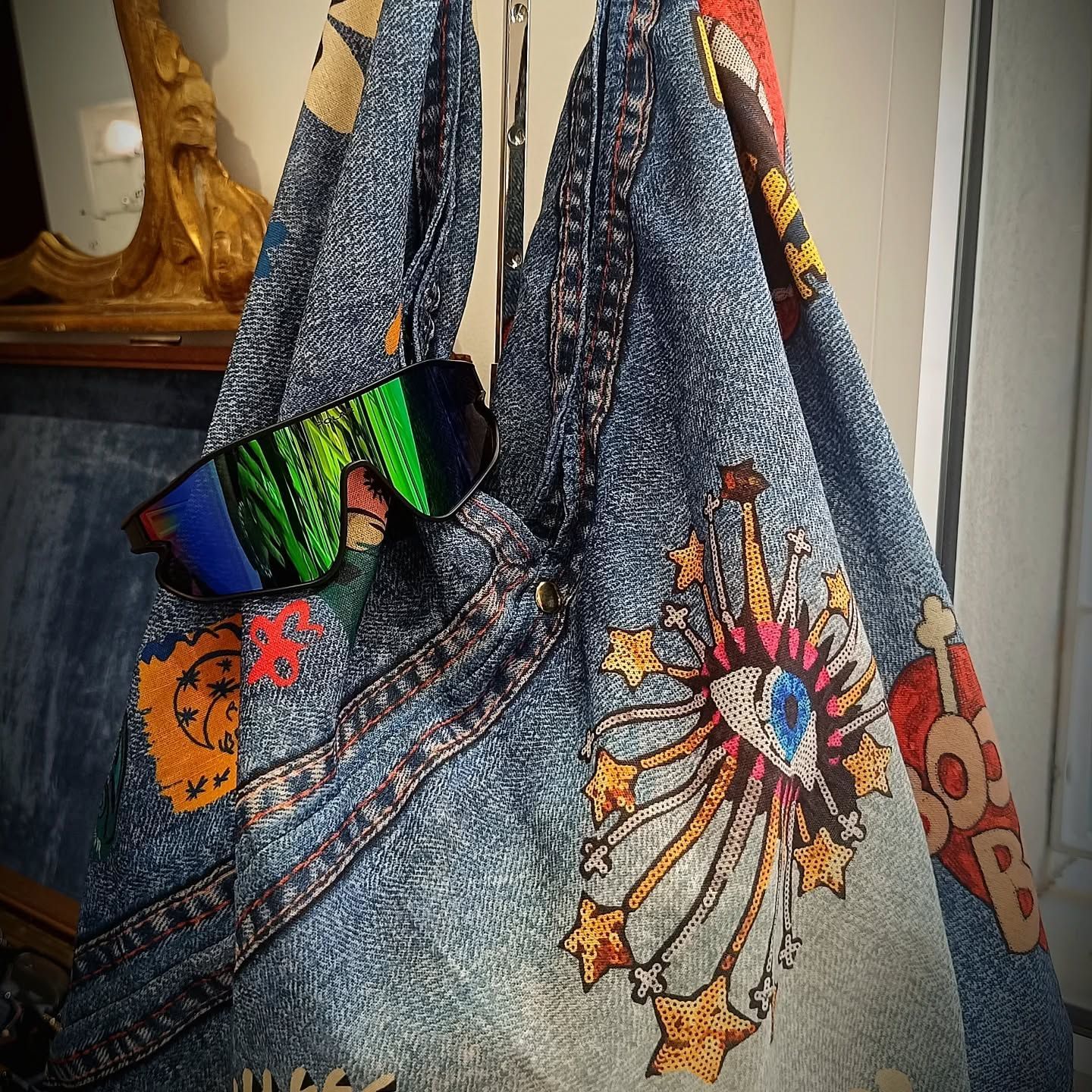 Borsa tote in denim blu con toppe colorate e occhiali da sole appesi