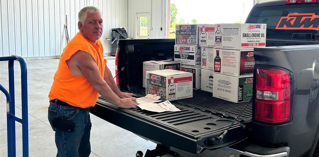 Man in orange shirt loading cases of beer into truck.
