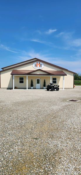 Building with beige walls, brown roof, and a logo sign under a blue sky. An ATV is parked in front.