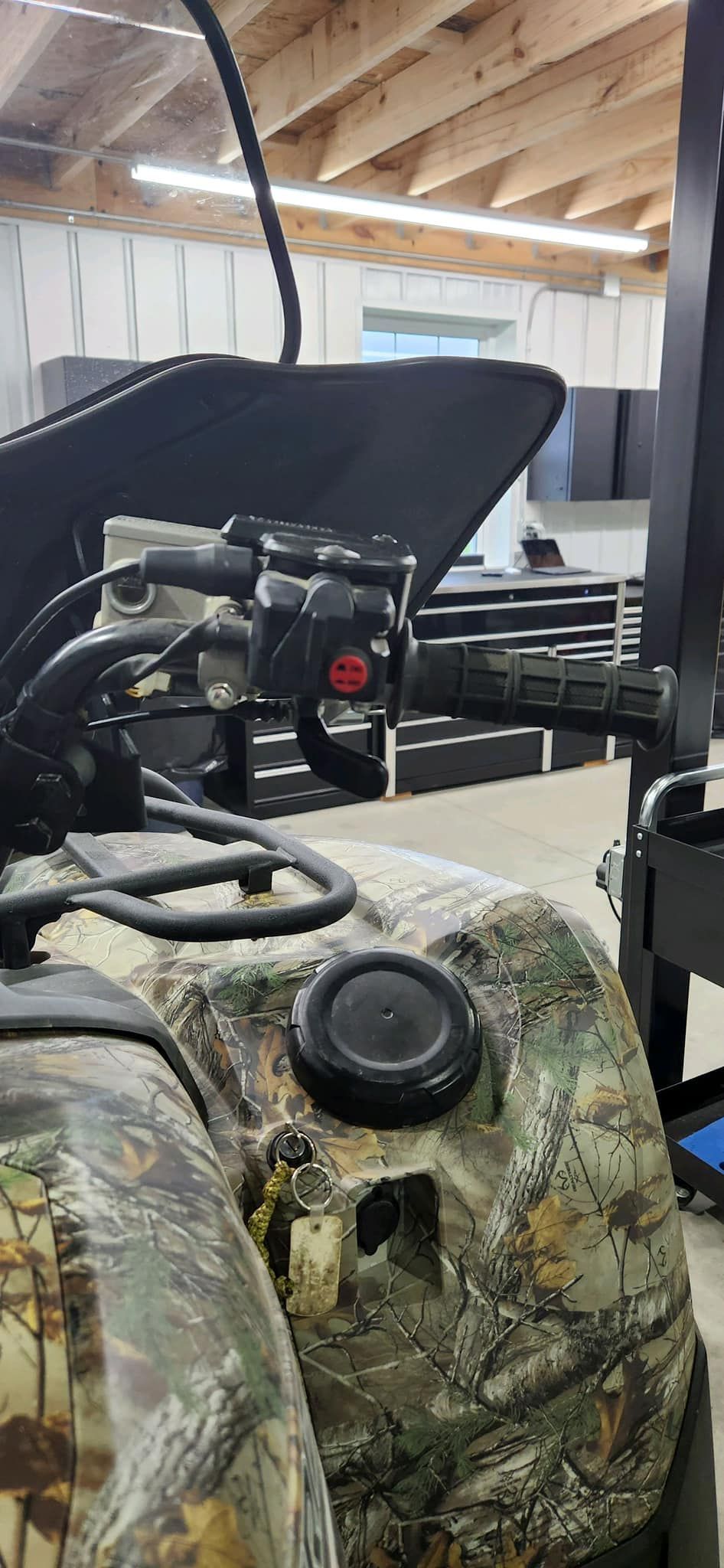 Camouflage ATV details: handlebars with controls, fuel tank, and windshield.