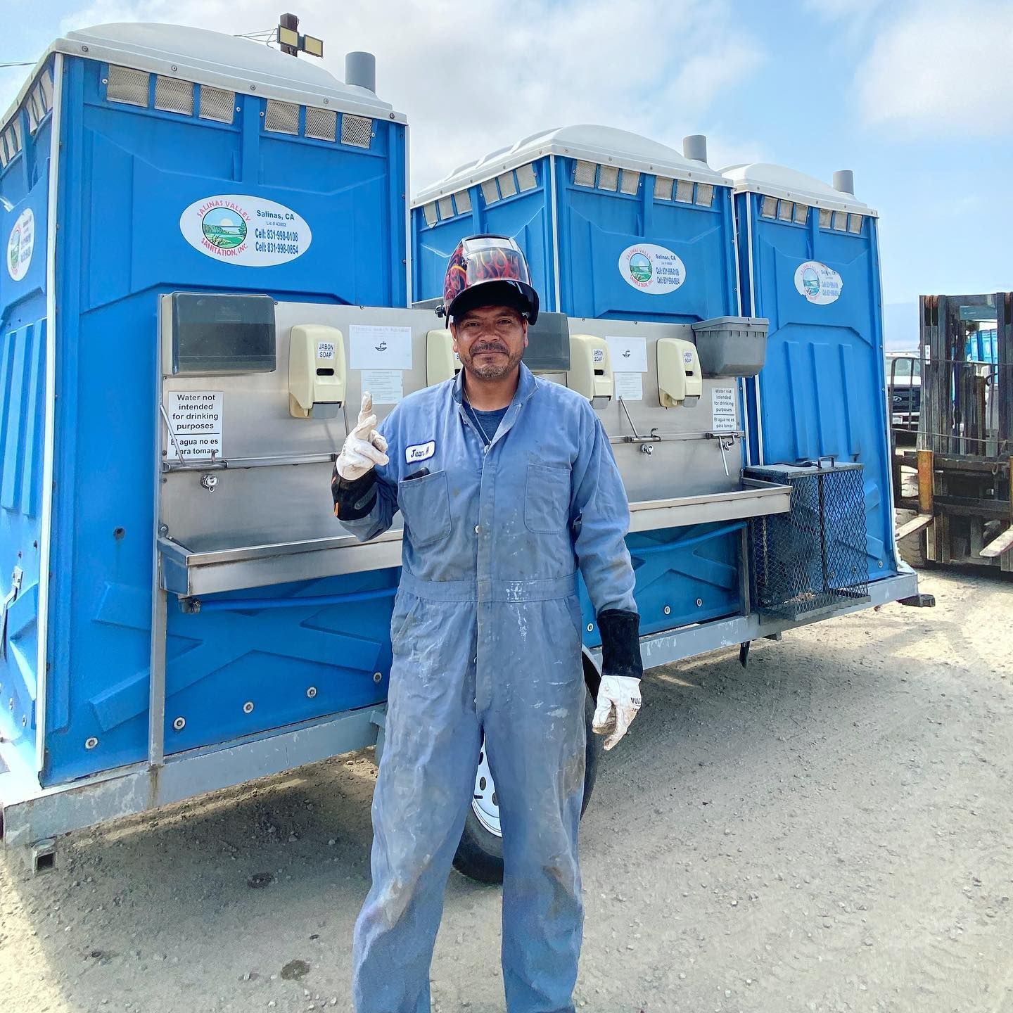 A man is standing in front of a row of blue portable toilets