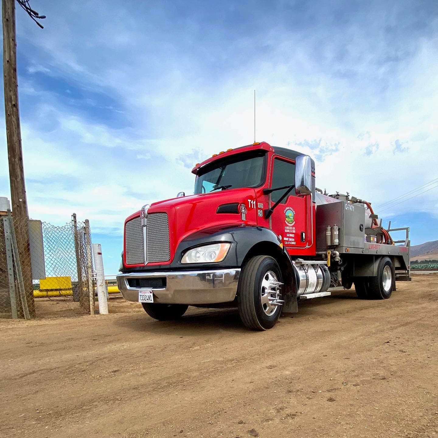 A red semi truck is parked on a dirt road