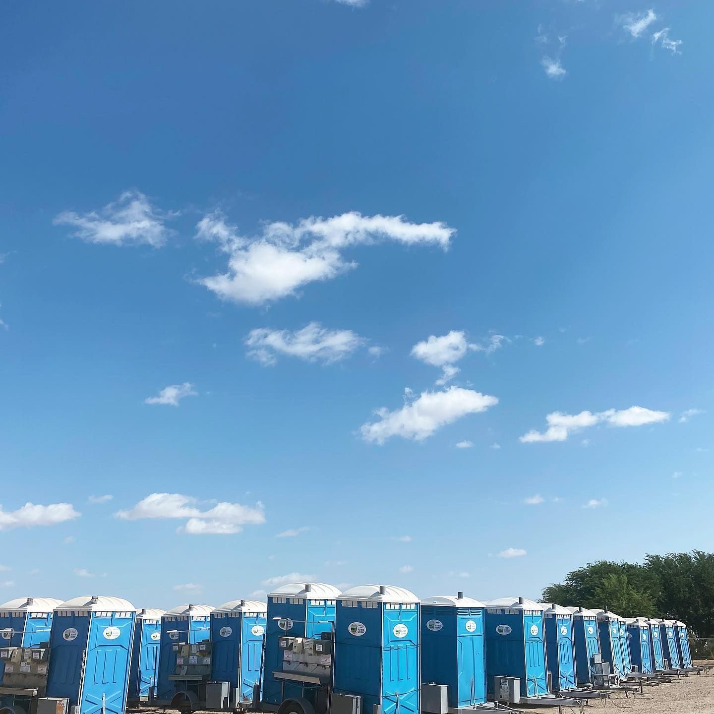 A row of blue portable toilets against a blue sky