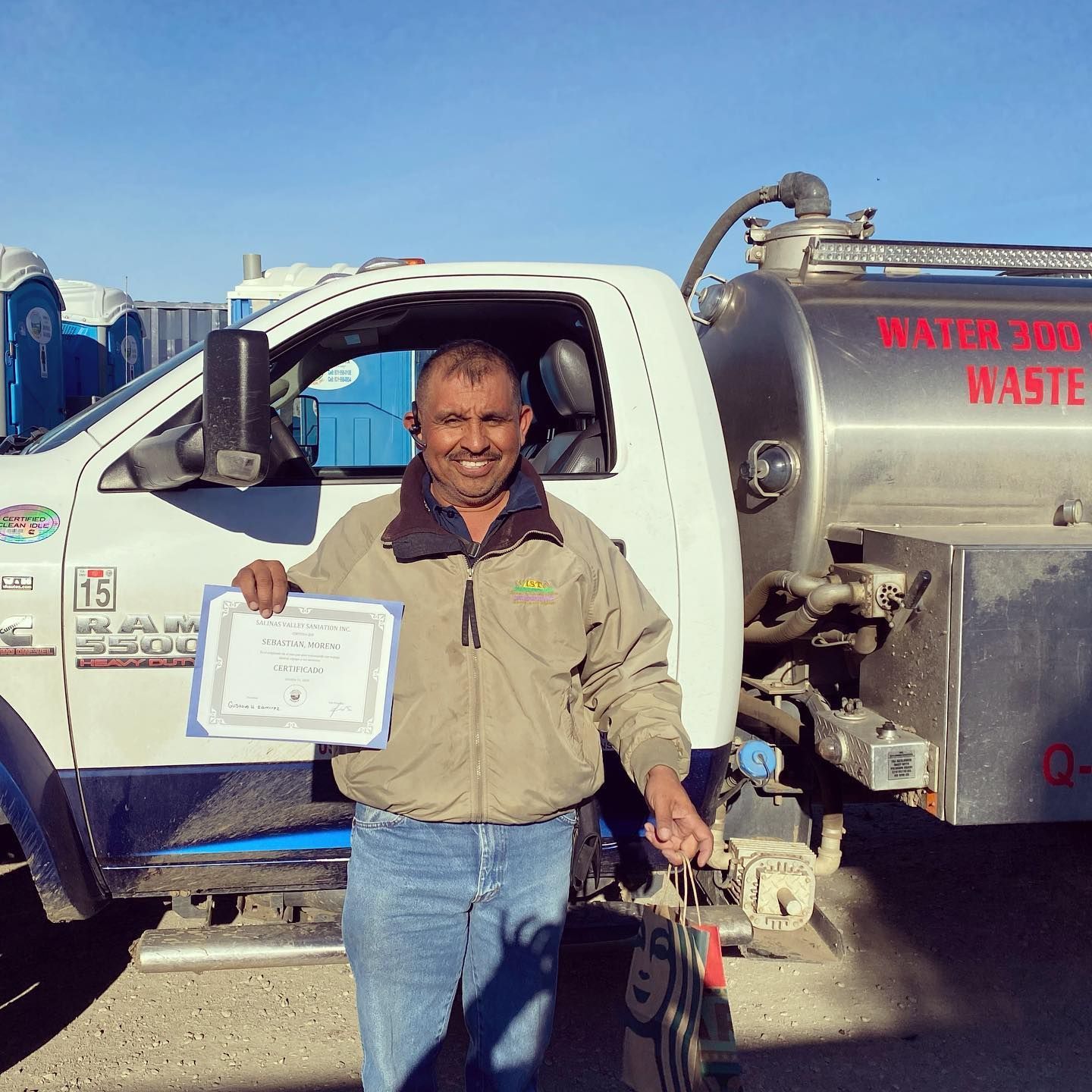 A man is standing in front of a water and waste truck
