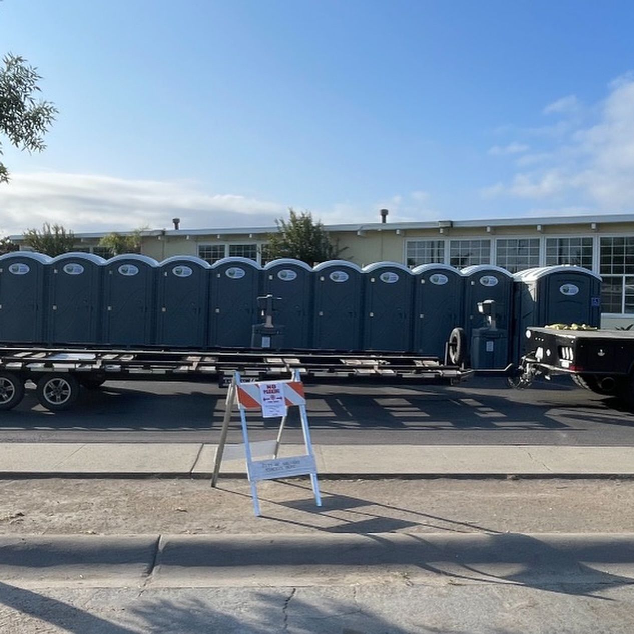 A trailer full of portable toilets is parked on the side of the road