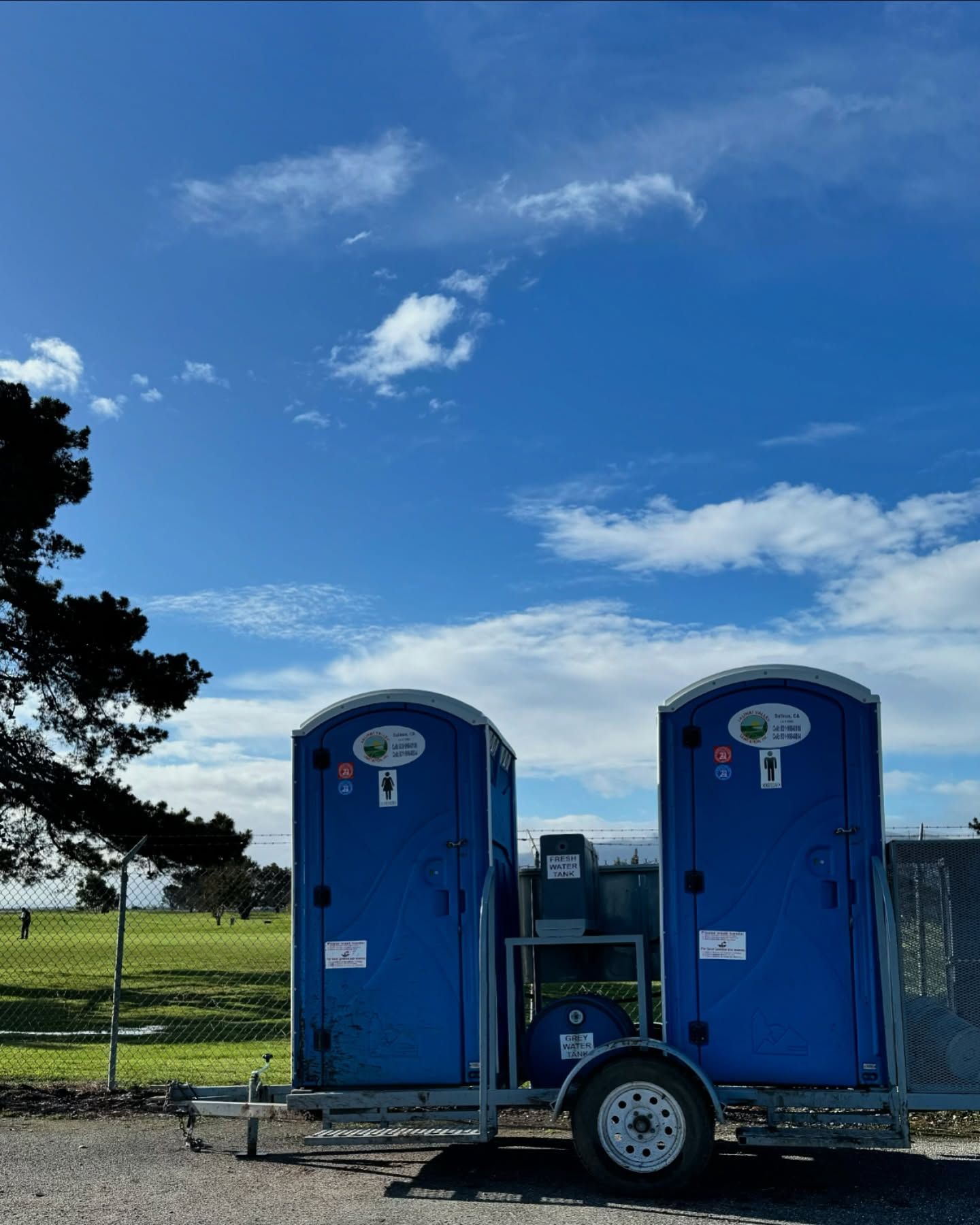 Two blue portable toilets are parked on a trailer.