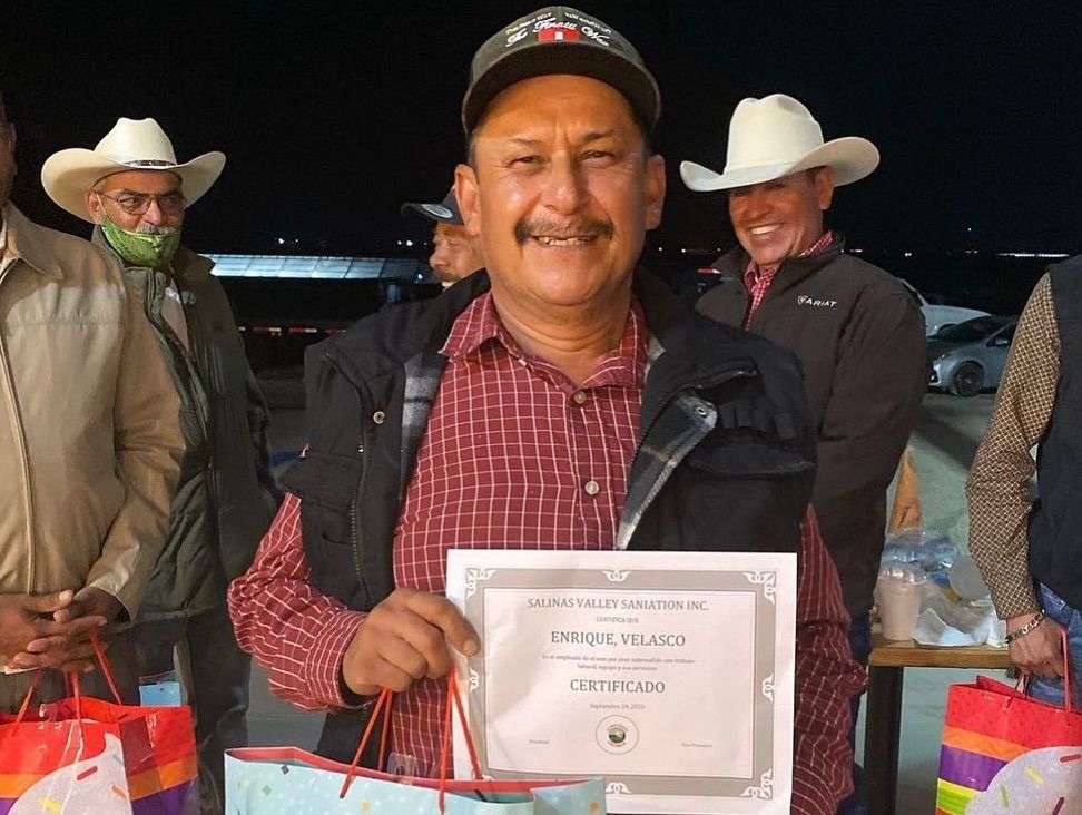 A man in a cowboy hat is holding a certificate