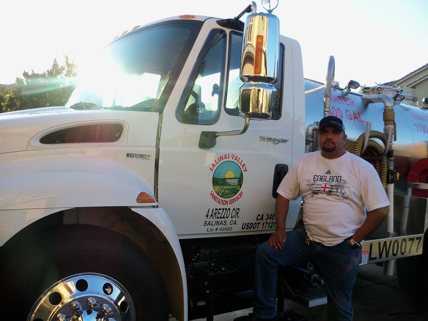 A man in a white shirt is standing next to a white truck