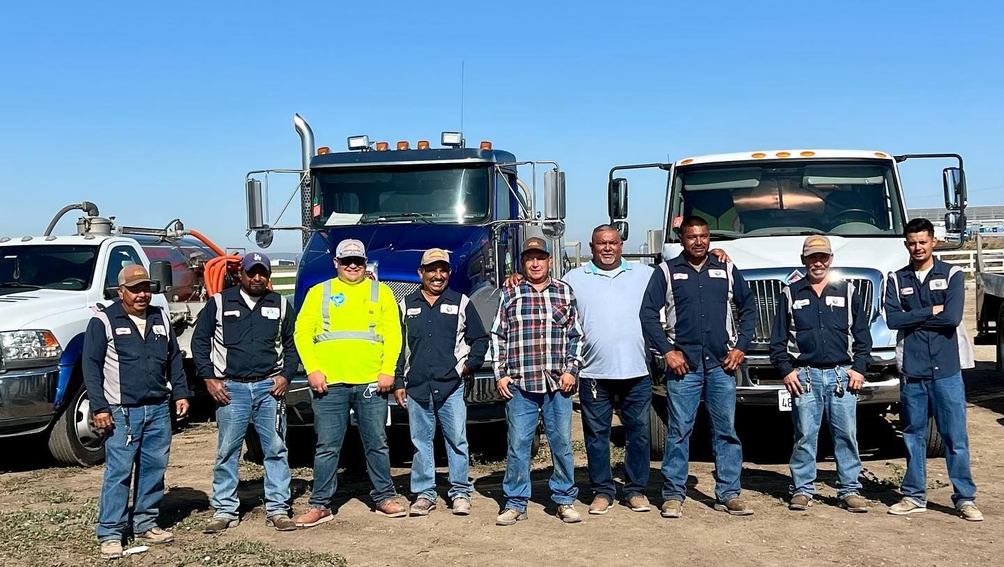 A group of men are posing for a picture in front of trucks.