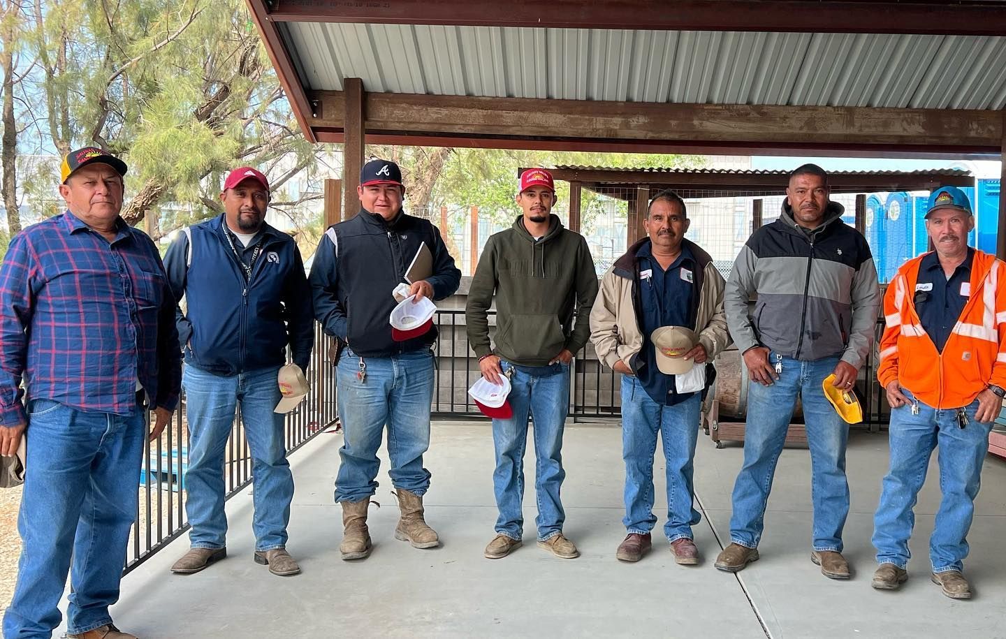 A group of men are standing next to each other under a covered area.