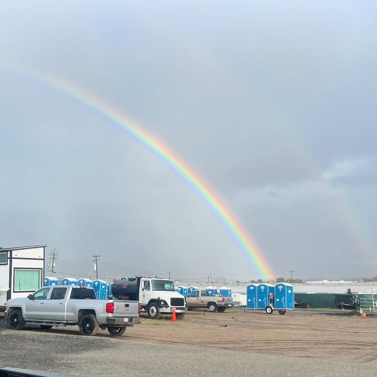 A rainbow is visible in the sky above a parking lot