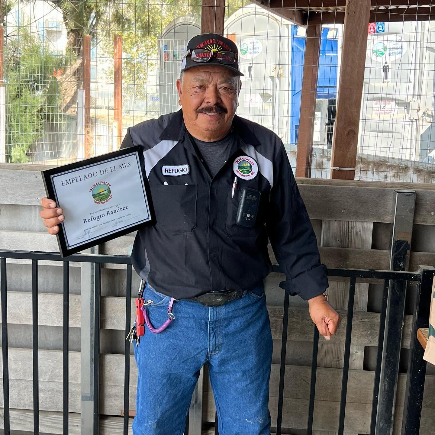 A man with a mustache is holding a framed certificate