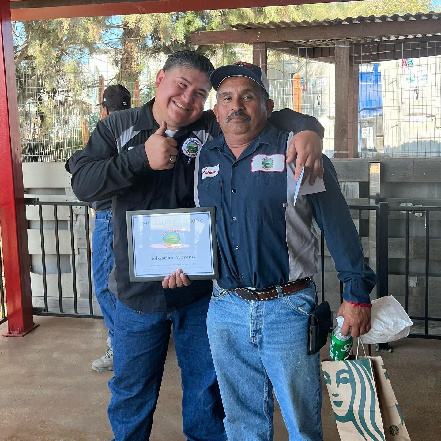 Two men are posing for a picture and one is holding a certificate