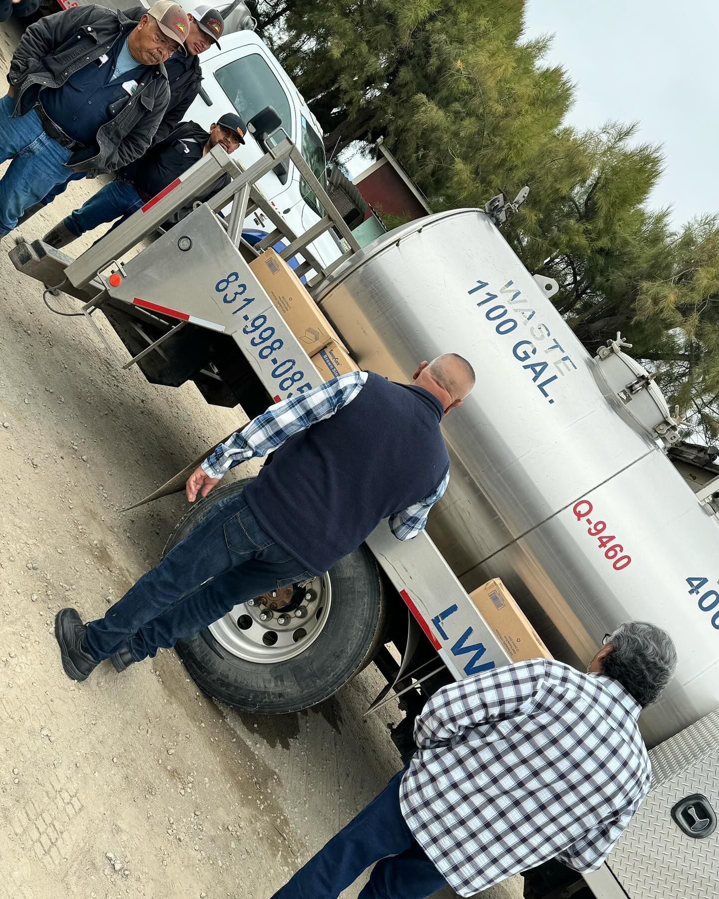 A group of men are standing next to a tanker truck.