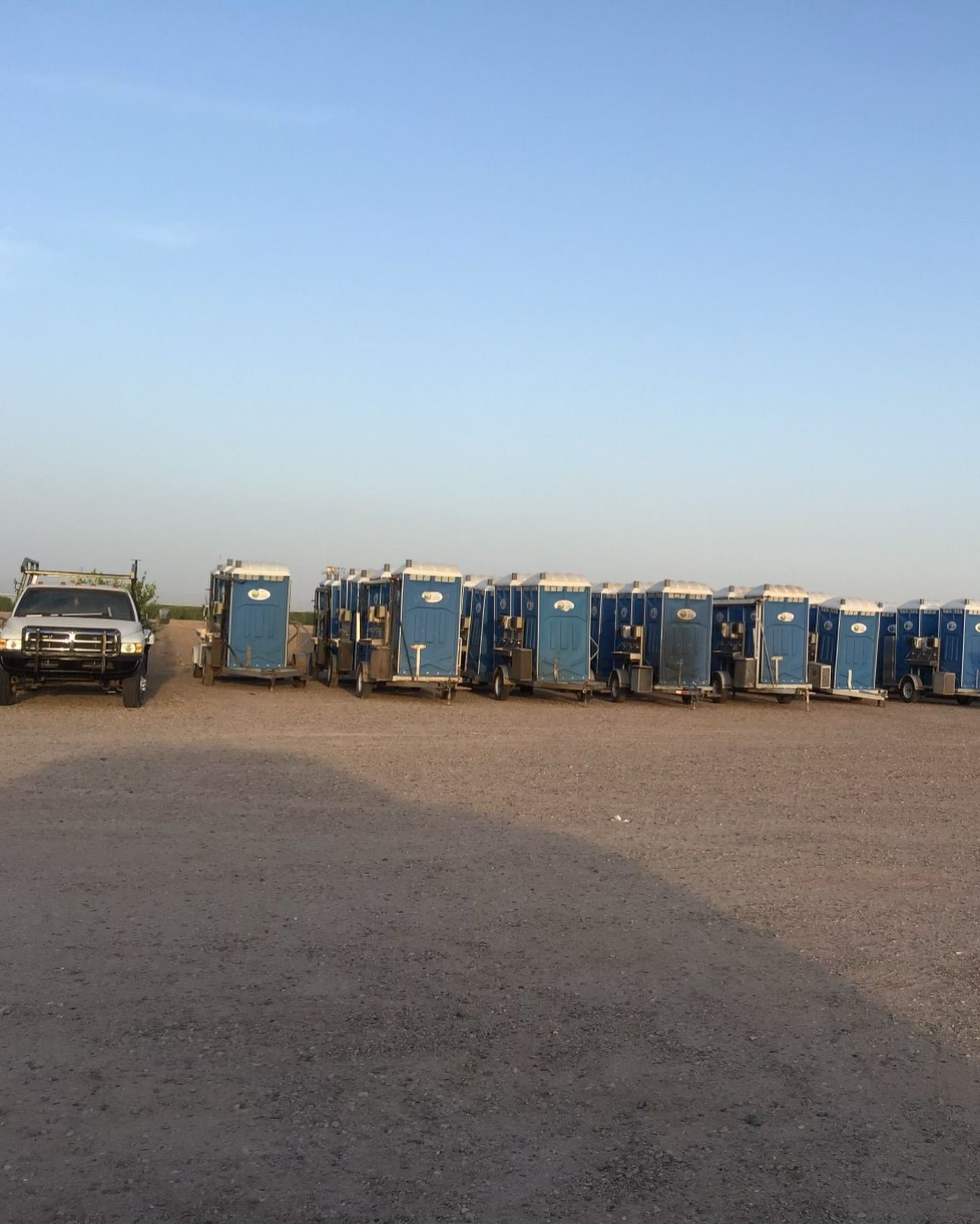 A row of portable toilets are lined up in a parking lot