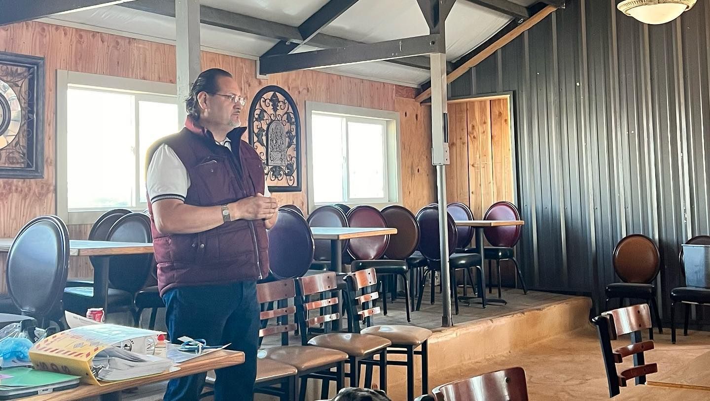 A man is standing in a restaurant talking on a cell phone.