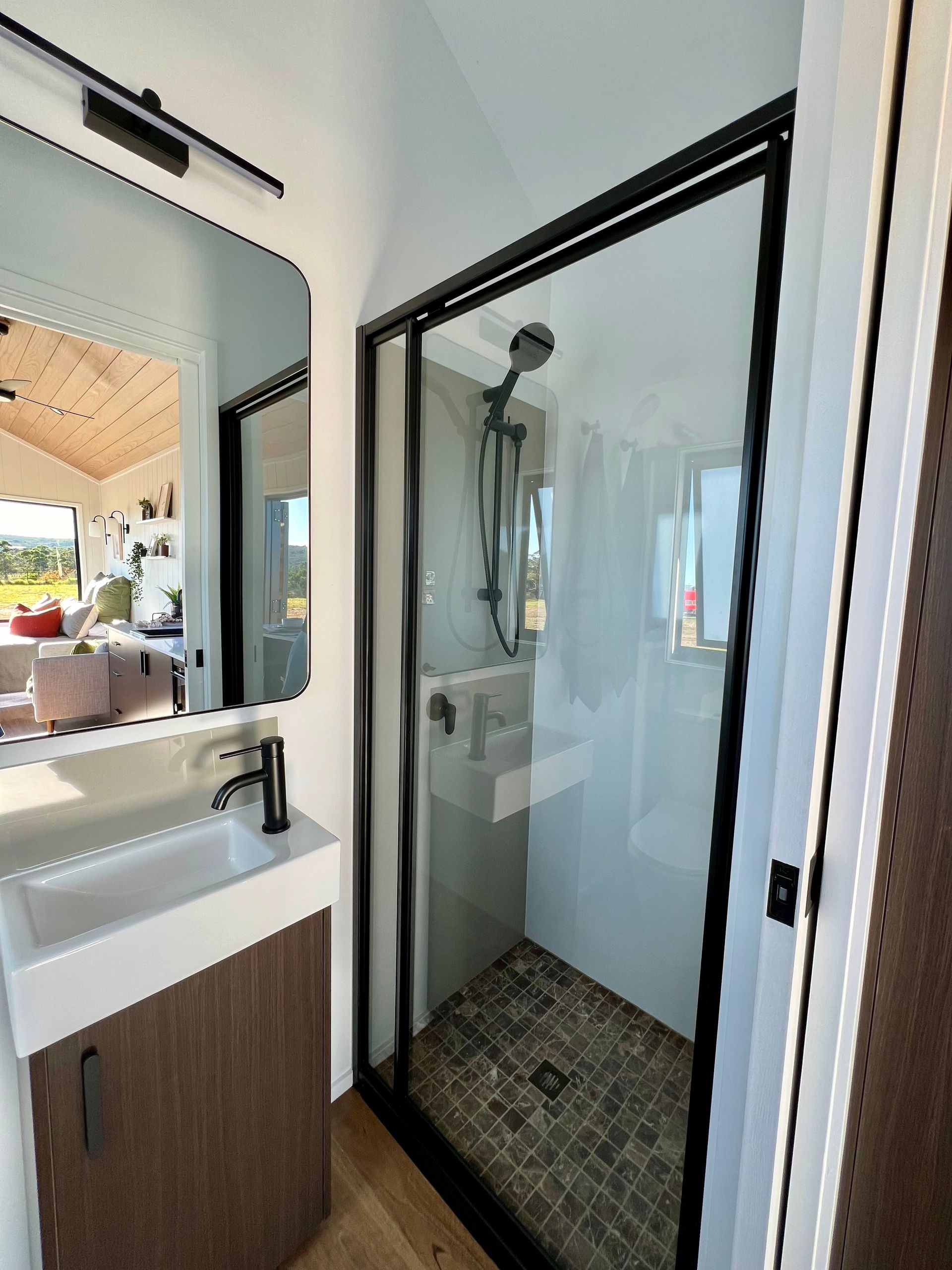 Small modern bathroom with a glass shower, sink, and mirror.