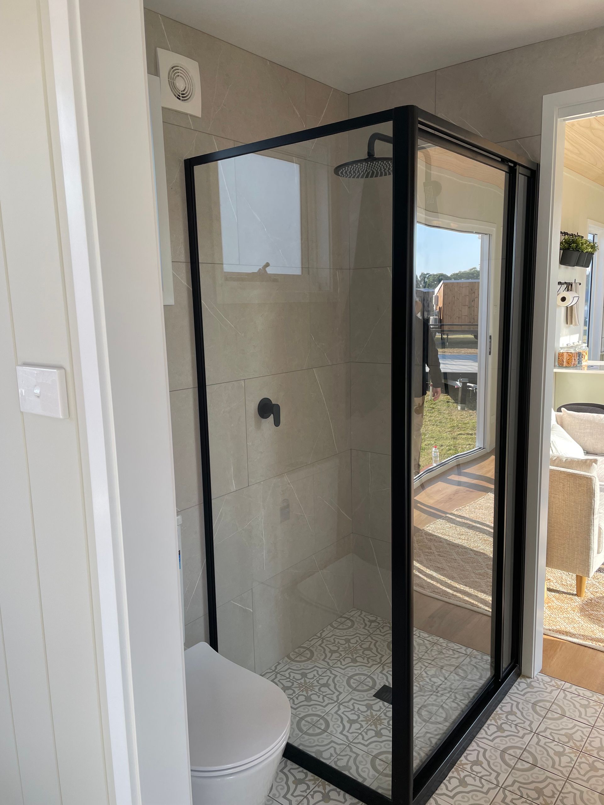 Black-framed glass shower enclosure in a bathroom with a toilet.