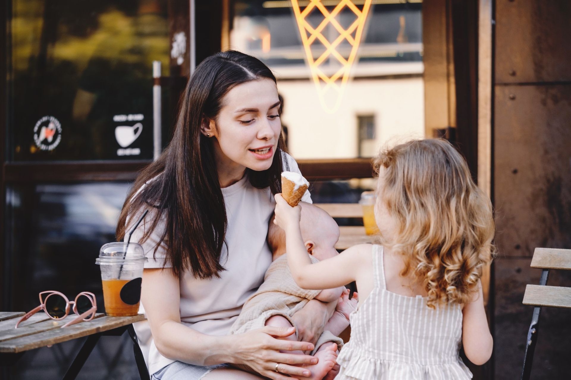 Woman sharing a popsicle with a child at an outdoor café table