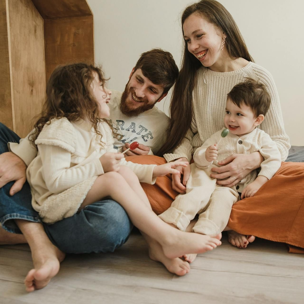 Family sitting on the floor, smiling and cuddling together in a cozy living room