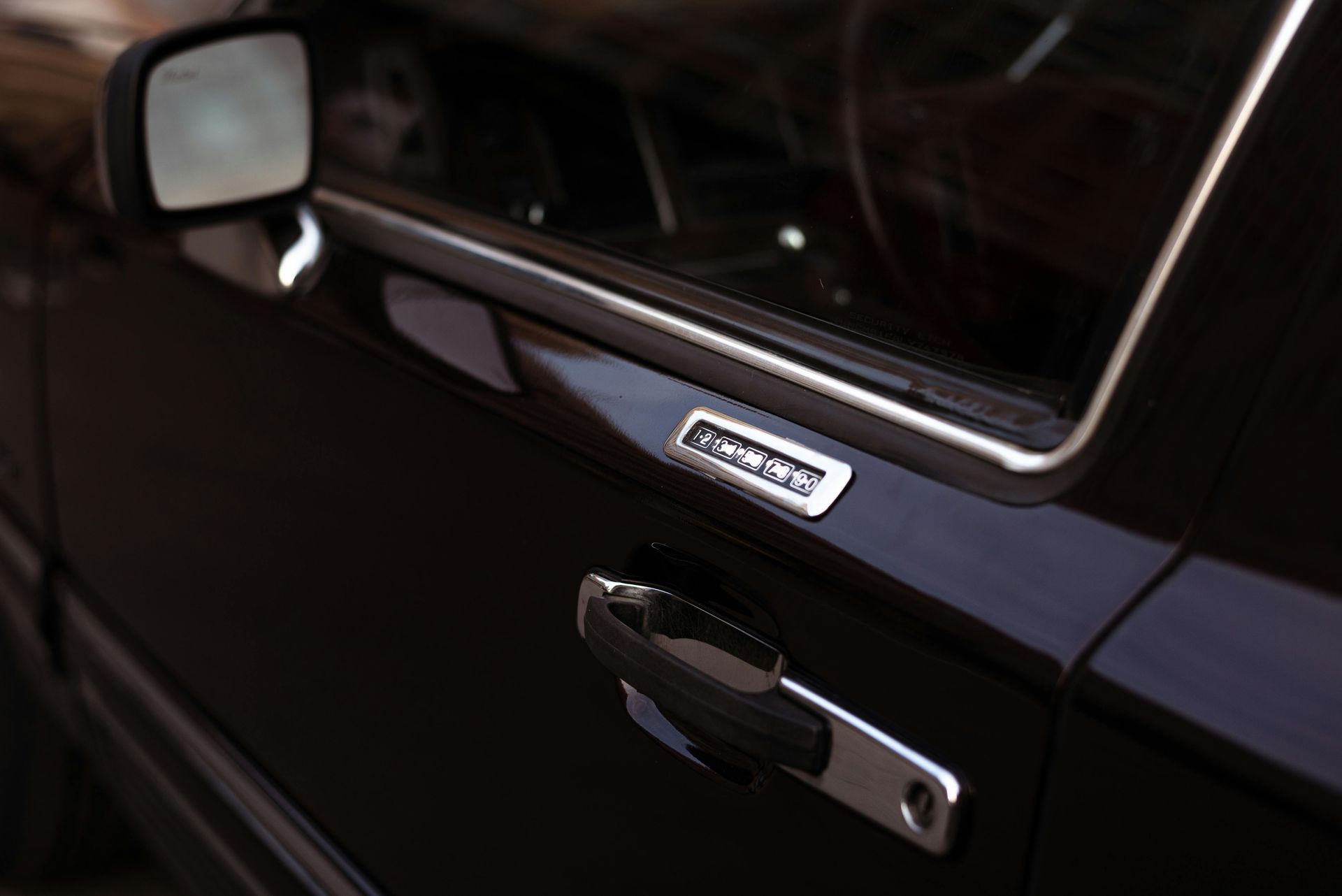 Close-up of a black car door with side mirror and chrome handle