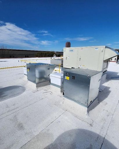 Rooftop HVAC units on a snowy flat roof under a clear blue sky.