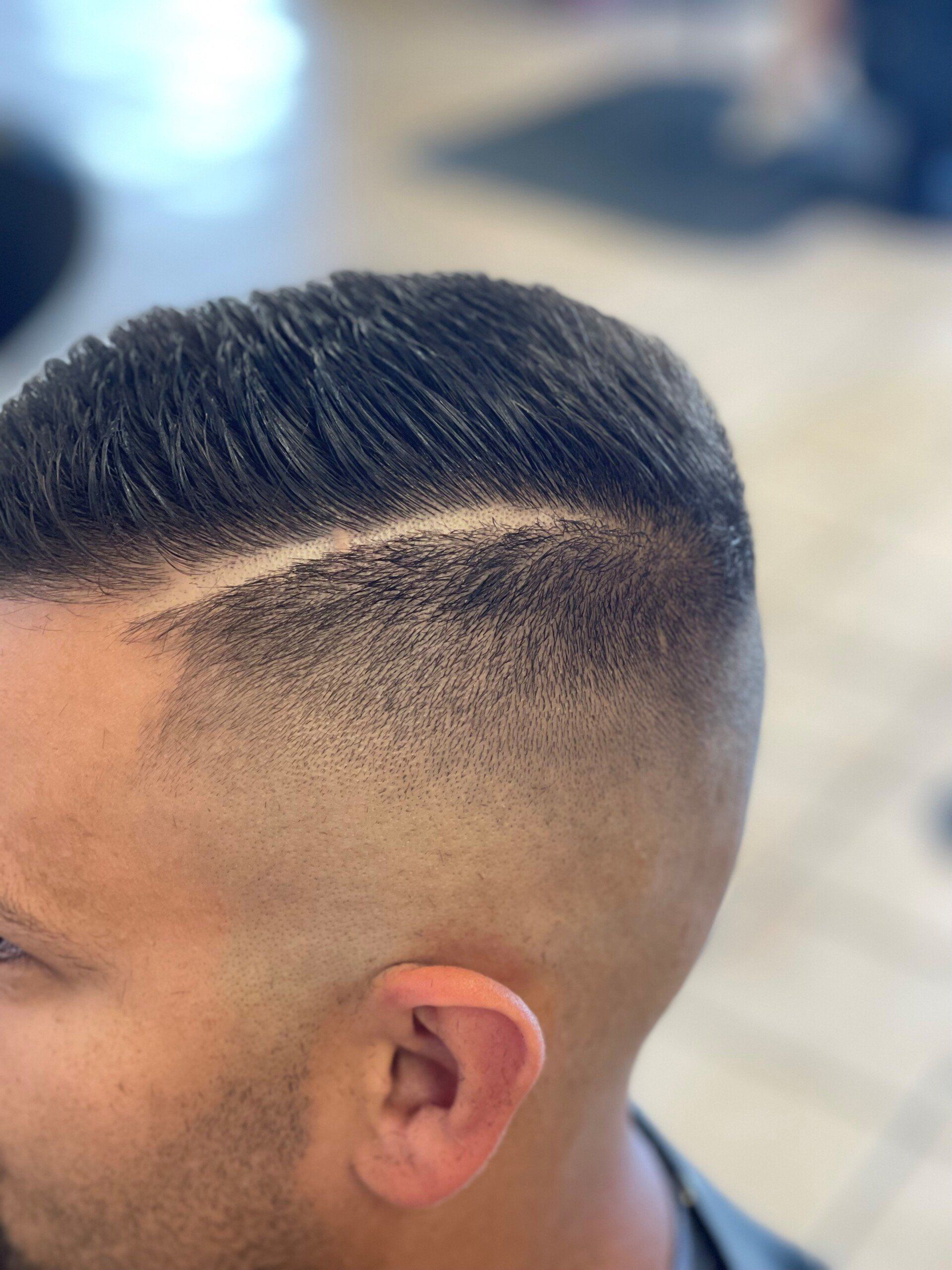 A man is getting his hair cut at a barber shop.