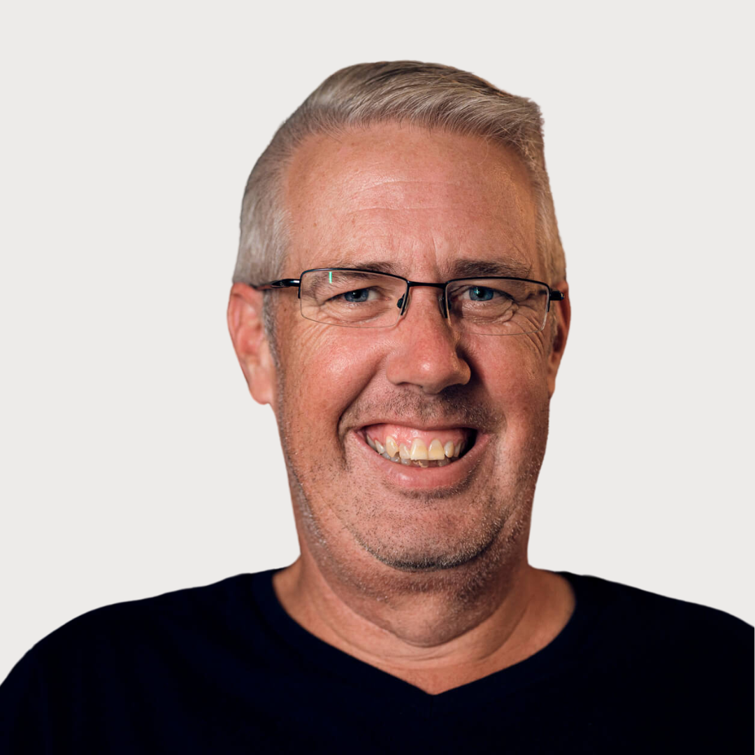 Smiling man with gray hair and glasses wearing a black shirt.