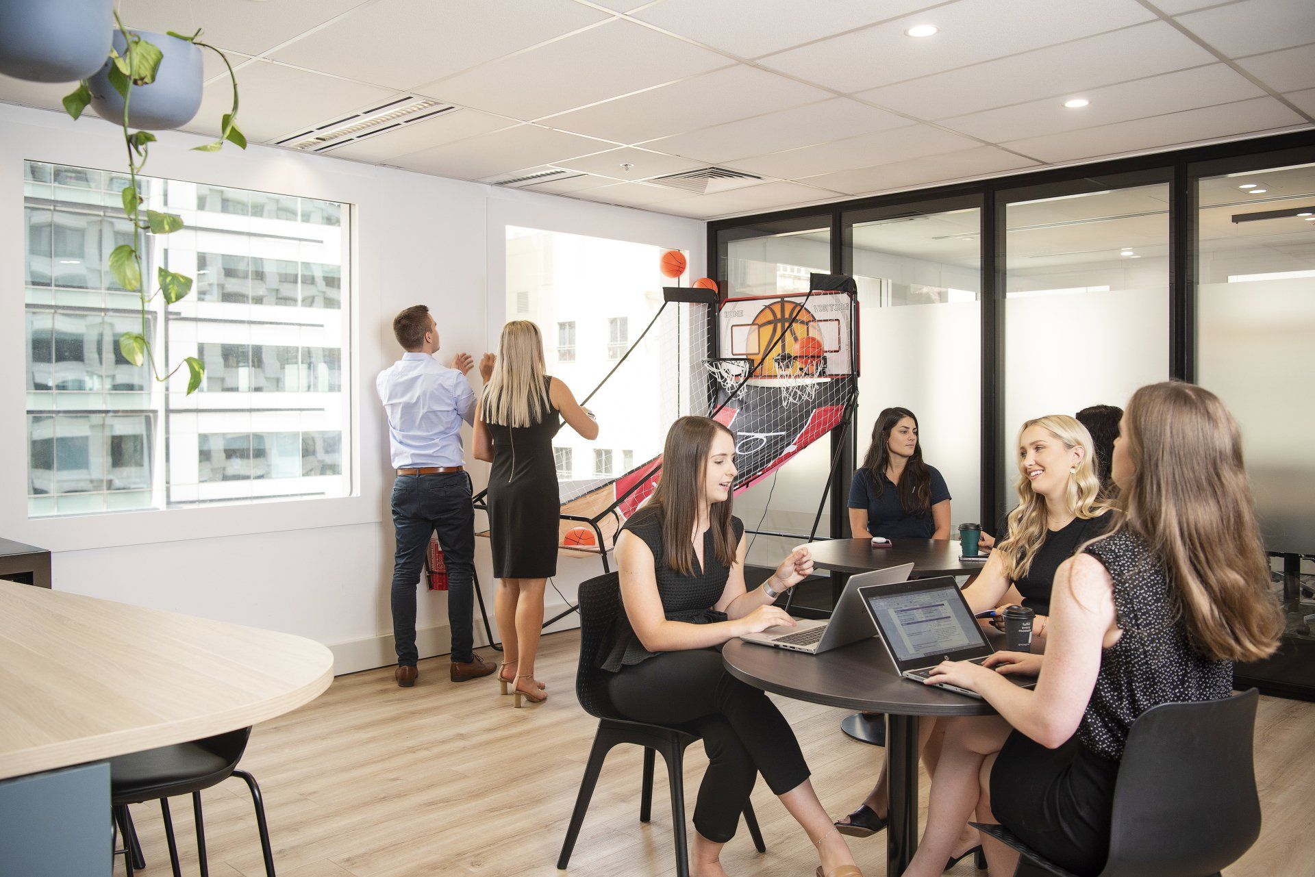 Office space: People working at tables, others playing basketball.