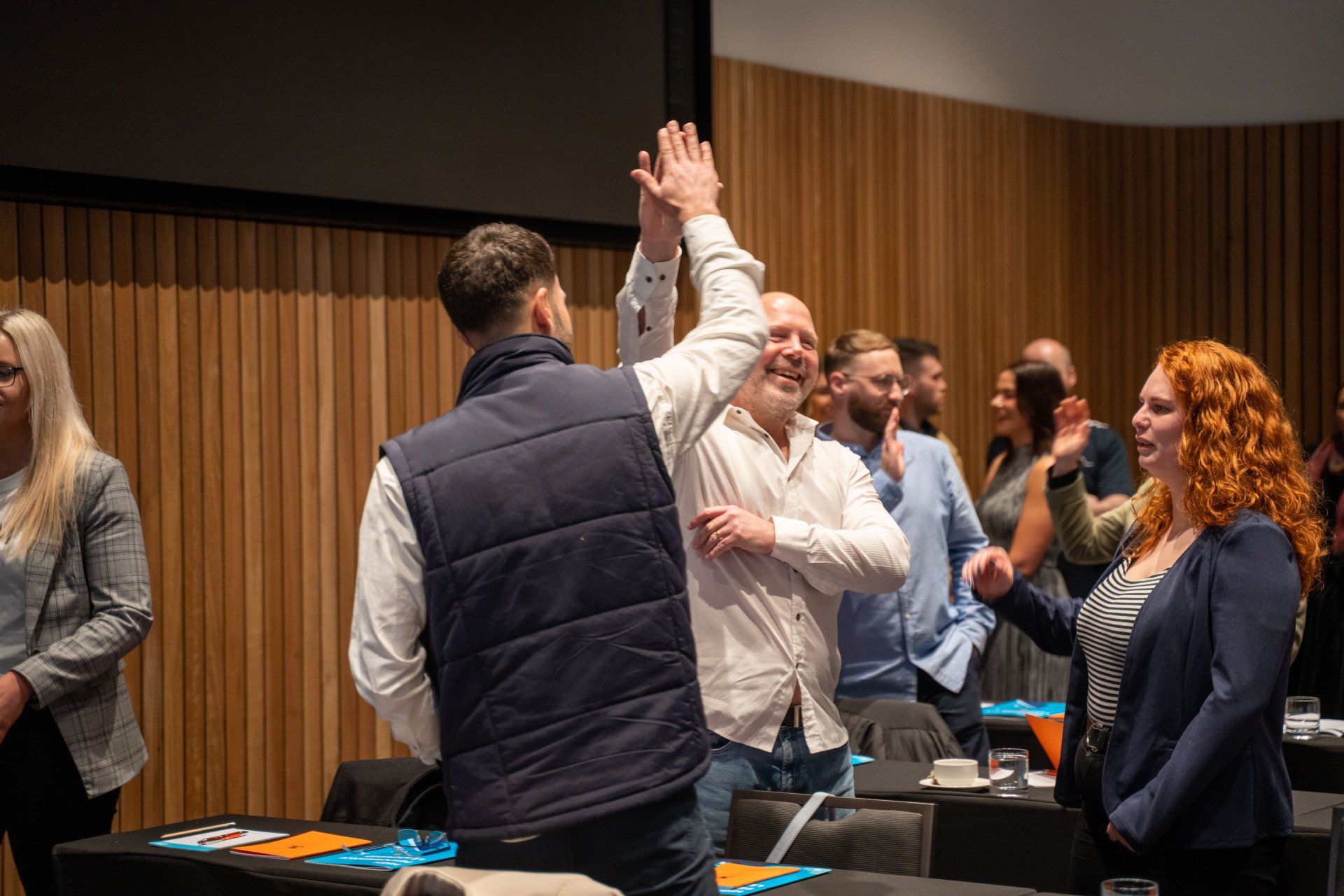 People in a conference room celebrate with high-fives.