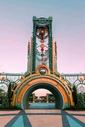 Decorative illuminated archway and clock tower at dusk, with colorful lights and a walkway leading through it