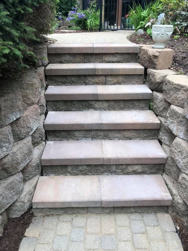 Stone steps leading up through a garden path with greenery on both sides.